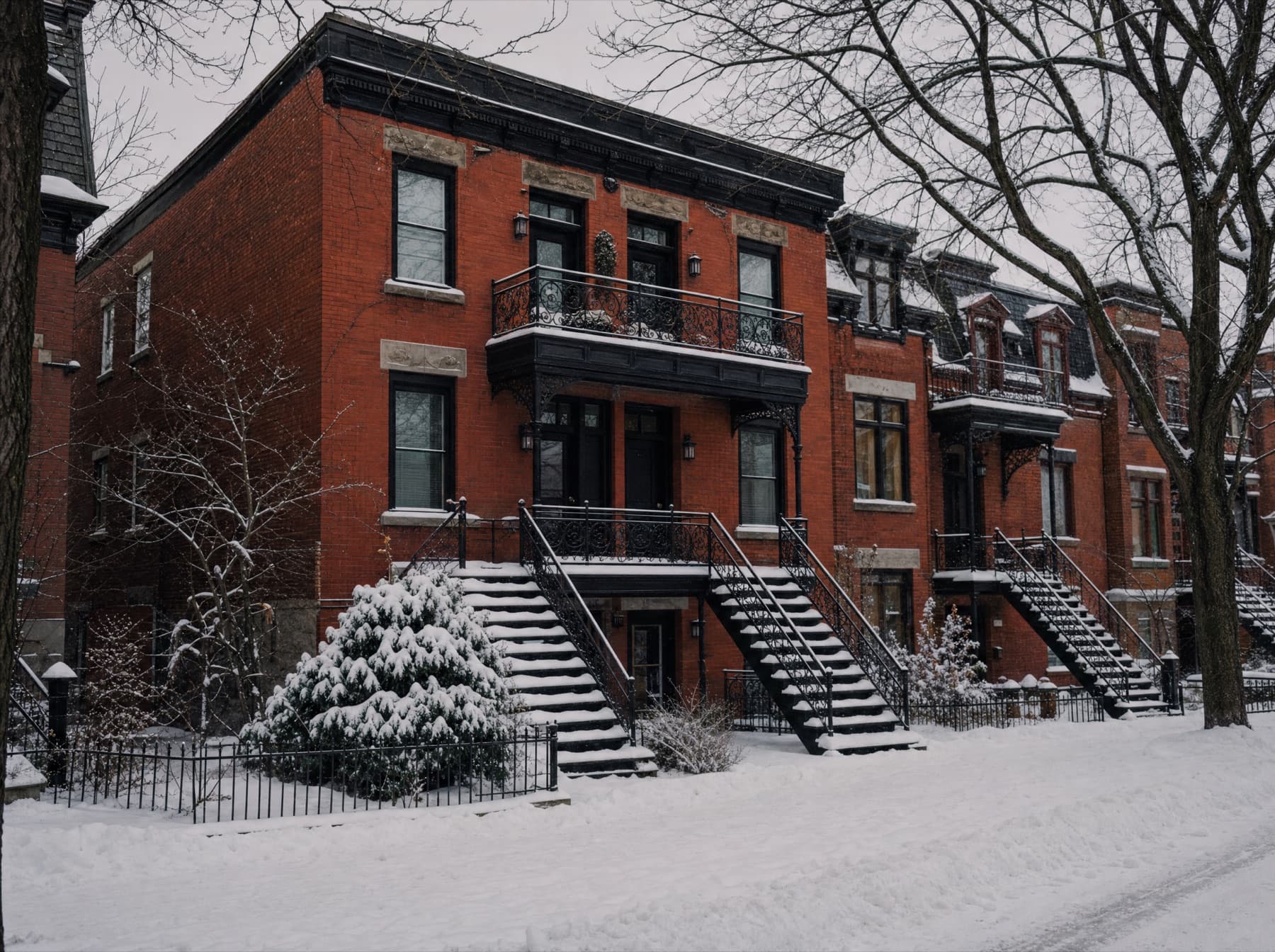 Snow-dusted brick apartment facades with exterior staircases in Montréal